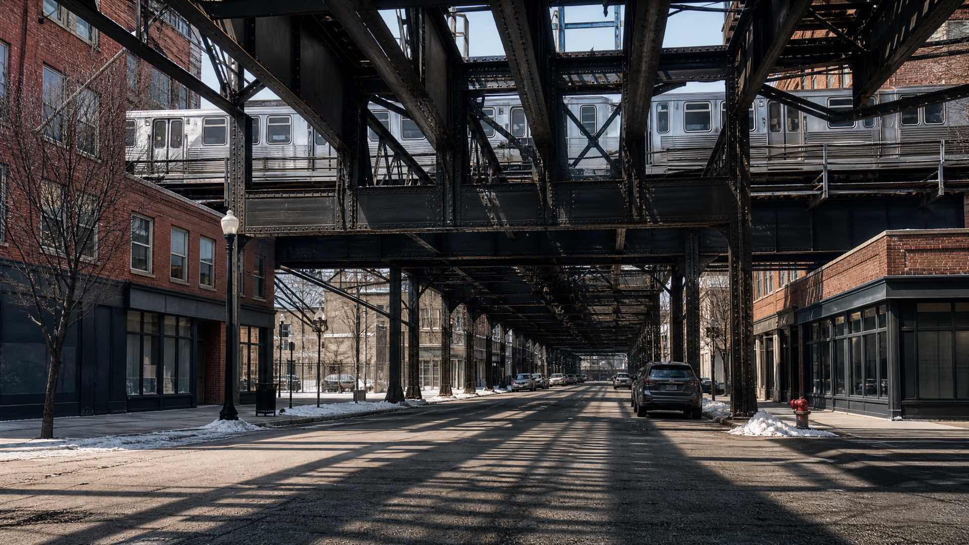 A Chicago commercial street beneath an elevated steel railway, red brick shopfronts either side in cold winter light