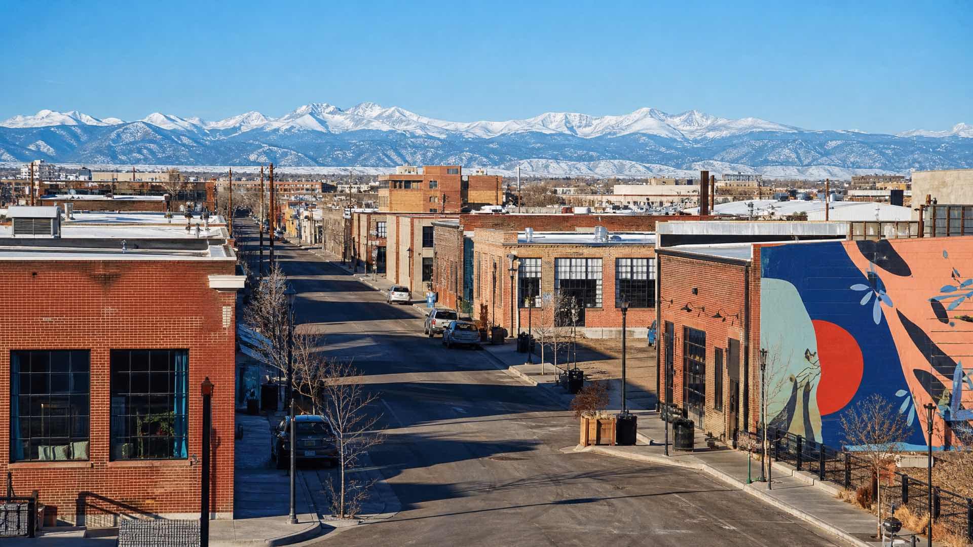 Converted brick industrial buildings in a Denver arts district with the snow-capped Rocky Mountain front range on the horizon